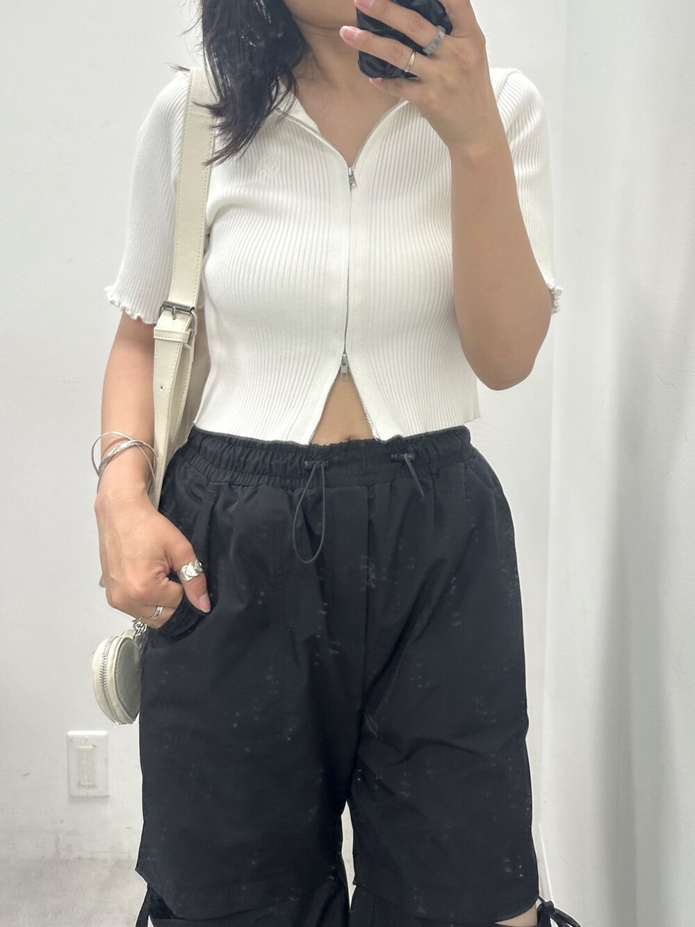 ブラック系のカーゴパンツ、ホワイト系のTシャツ/カットソー、ホワイト系のボディバッグ/ウエストポーチを着用したレディースの夏コーディネートの2枚目の写真