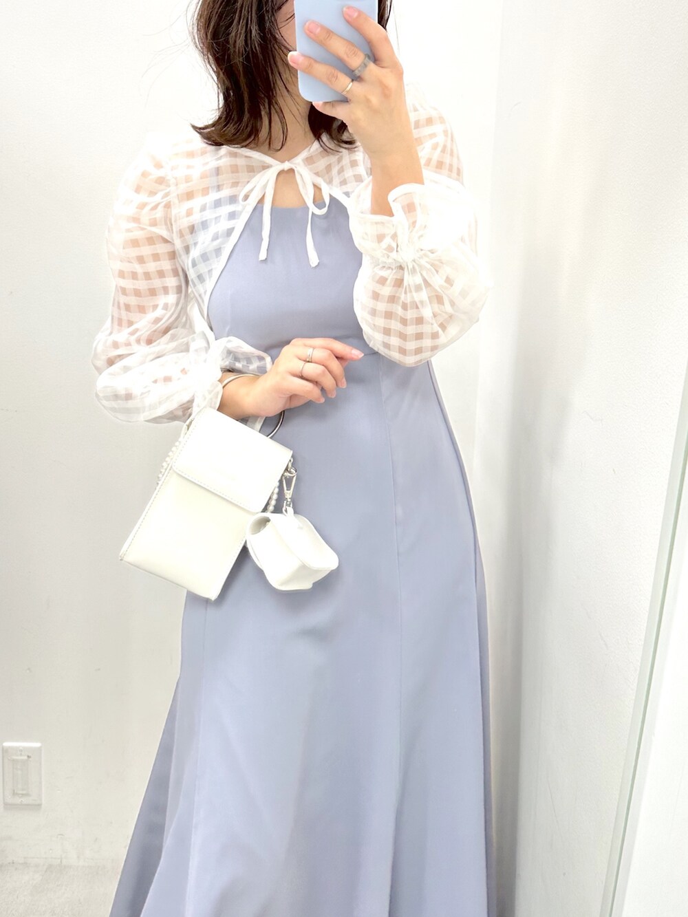 ブルー系のワンピース、ホワイト系のショルダーバッグ、ホワイト系のスニーカーを着用したレディースの冬コーディネートの2枚目の写真