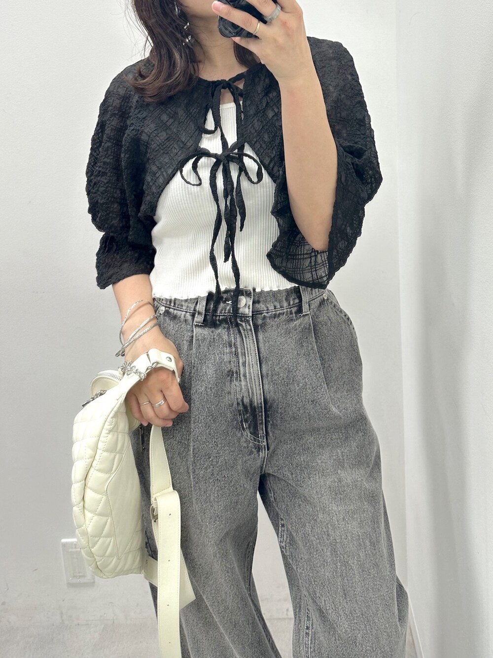 ブラック系のデニムパンツ、ブラック系のシャツ/ブラウス、ホワイト系のボディバッグ/ウエストポーチを着用したレディースの春コーディネートの2枚目の写真