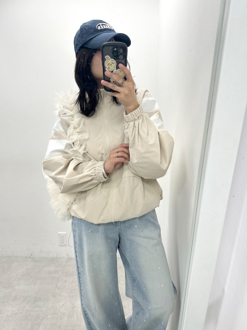 ベージュ系のマウンテンパーカー、ブルー系のデニムパンツ、ホワイト系のショルダーバッグを着用したレディースの春コーディネートの2枚目の写真