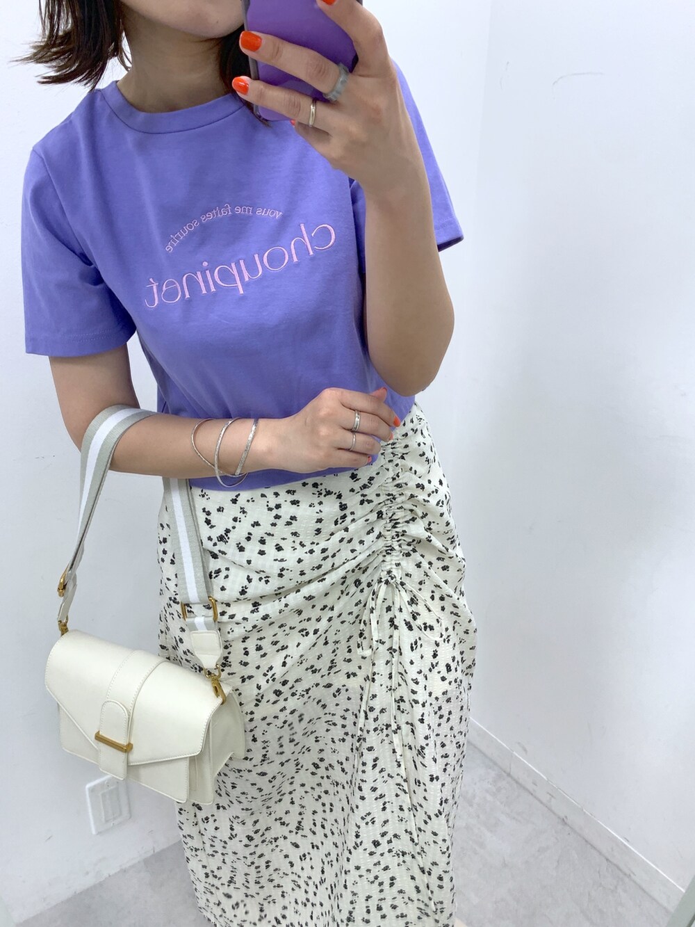 ホワイト系のスカート、パープル系のTシャツ/カットソー、ホワイト系のショルダーバッグを着用したレディースの春コーディネートの2枚目の写真