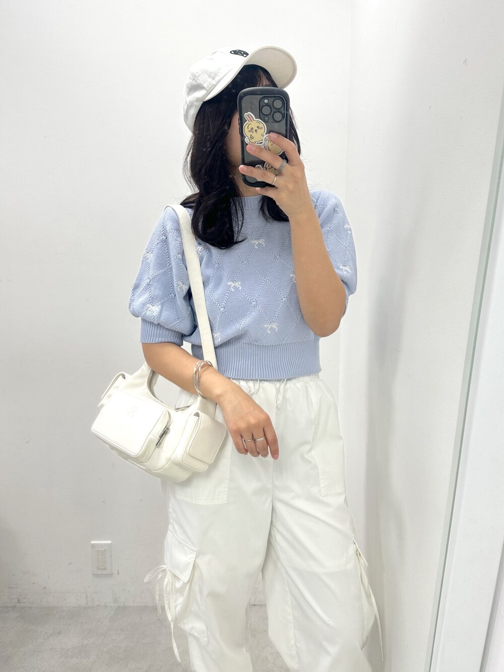 ホワイト系のショルダーバッグ、ホワイト系のカーゴパンツ、ブルー系のニット/セーターを着用したレディースの春コーディネートの2枚目の写真