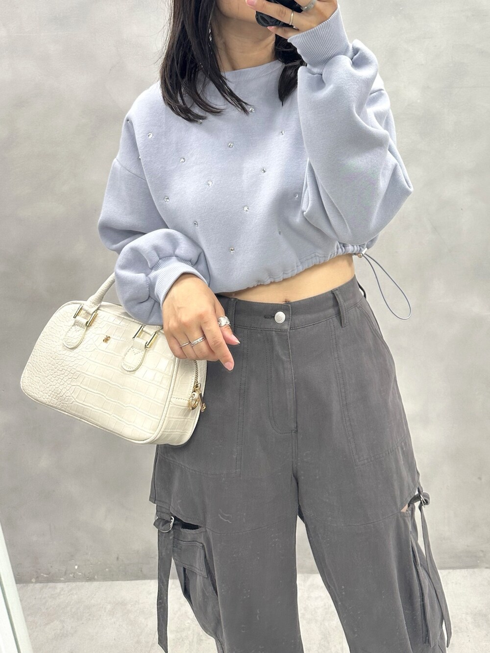 グレー系のカーゴパンツ、ブルー系のスウェット、ホワイト系のショルダーバッグを着用したレディースの秋コーディネートの2枚目の写真