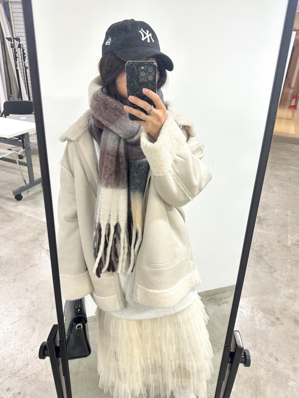 ホワイト系のムートンコート、ブラック系のショルダーバッグ、ホワイト系のスカートを着用したレディースの冬コーディネートの2枚目の写真