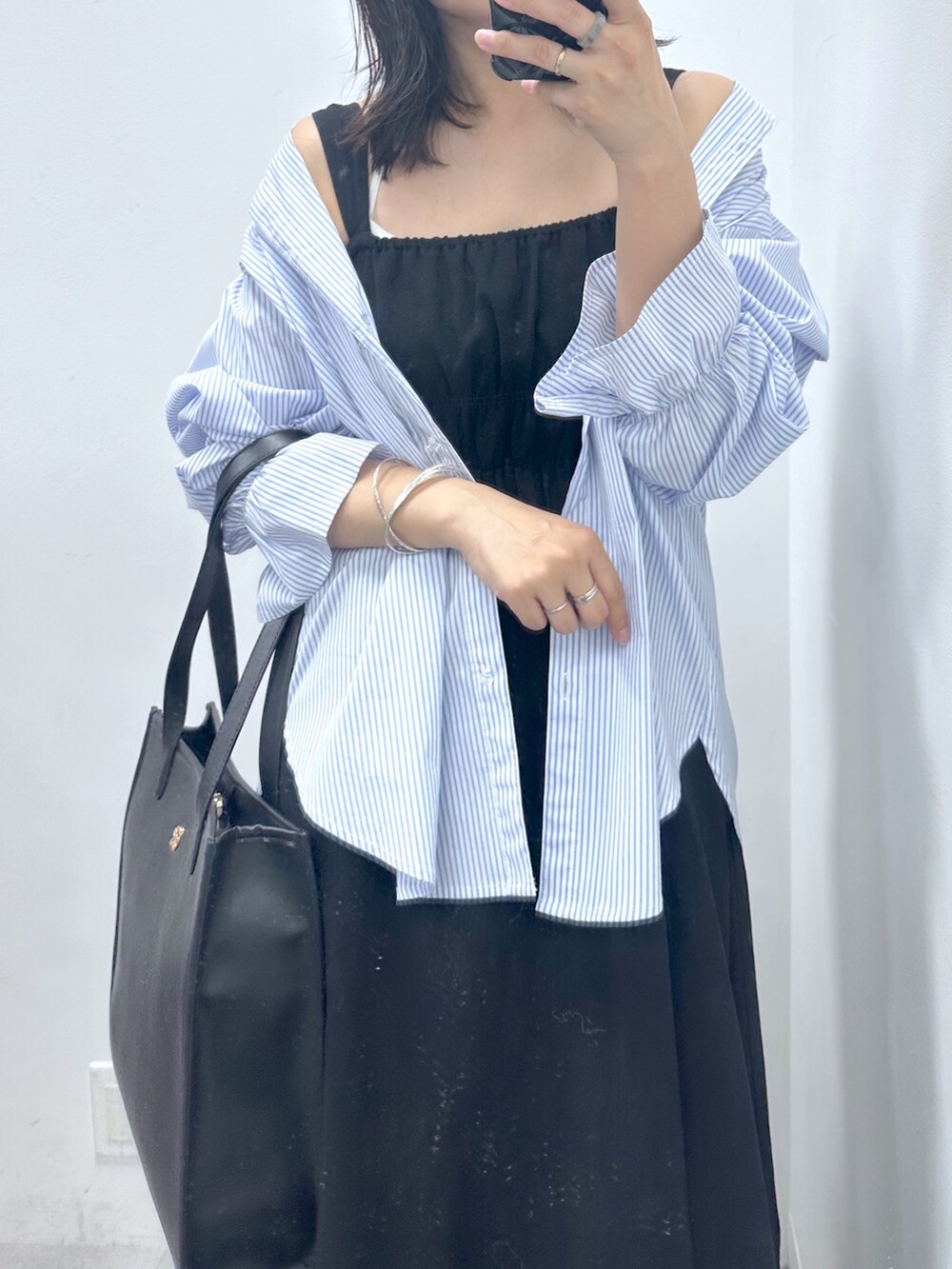 ブラック系のワンピース、ブラック系のトートバッグ、ブルー系のシャツ/ブラウスを着用したレディースの夏コーディネートの2枚目の写真