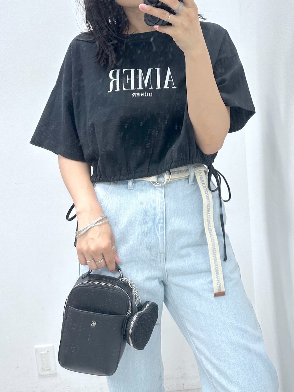 ブルー系のデニムパンツ、ブラック系のTシャツ/カットソー、ブラック系のショルダーバッグを着用したレディースの夏コーディネートの2枚目の写真