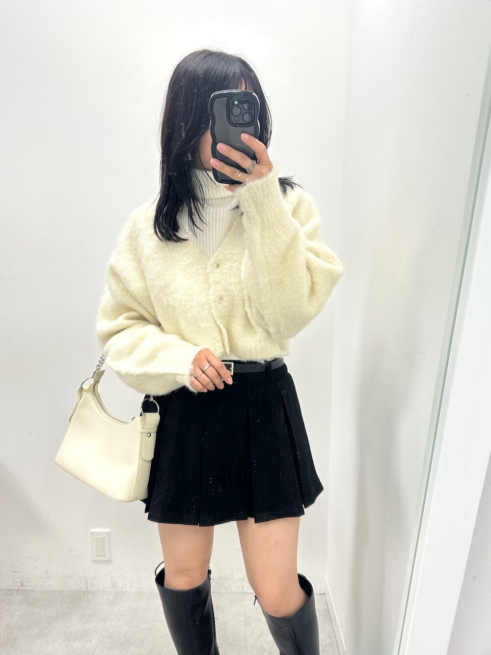 ブラック系のスカート、ホワイト系のカーディガン/ボレロ、ホワイト系のニット/セーターを着用したレディースの冬コーディネートの2枚目の写真