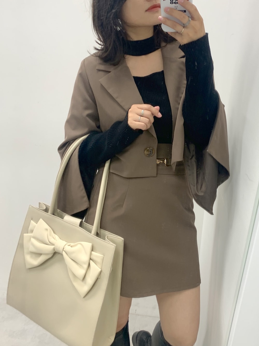 ブラウン系のスカート、ブラウン系のテーラードジャケット、ブラック系のニット/セーターを着用したレディースの夏コーディネートの2枚目の写真