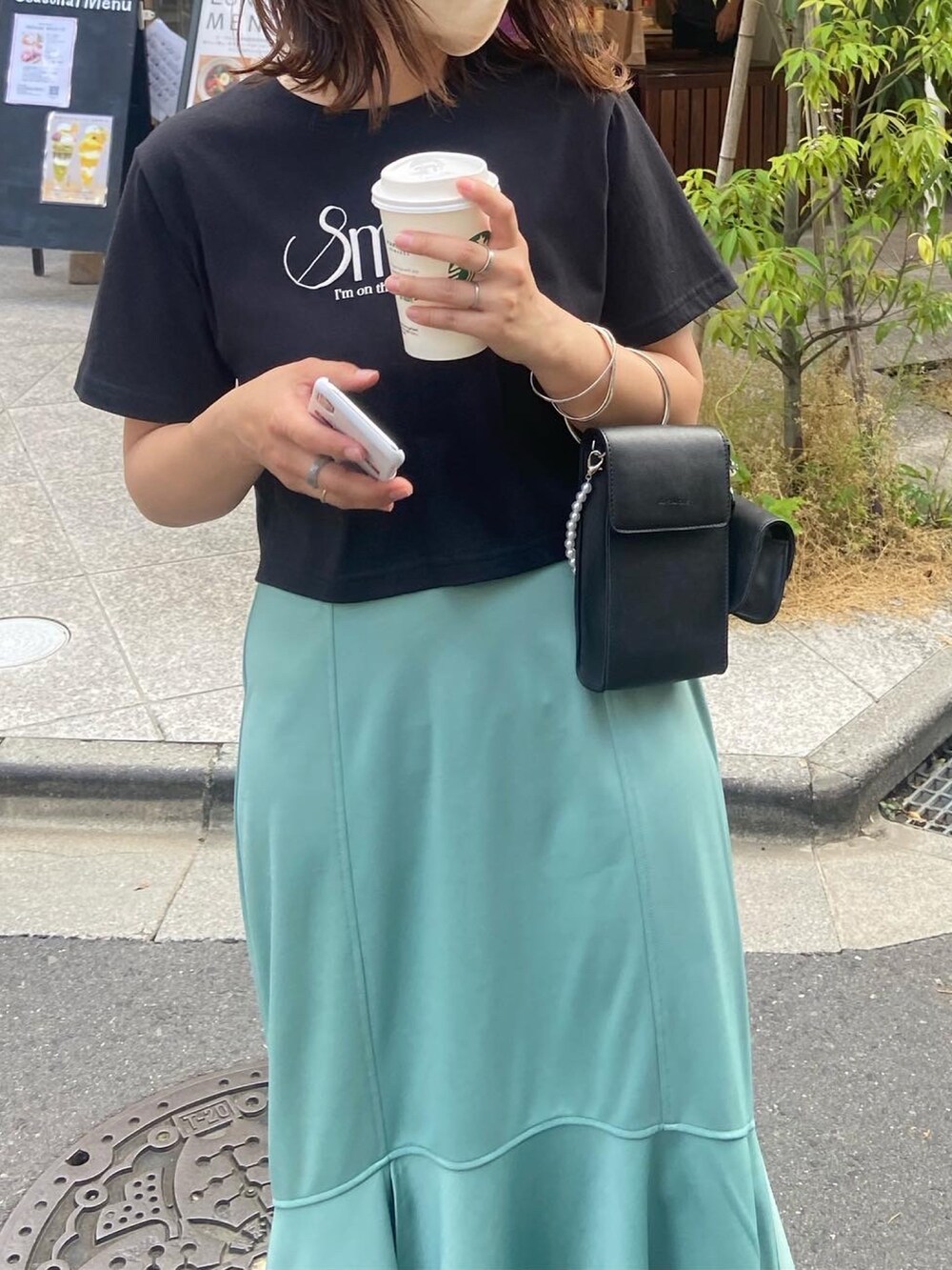 グリーン系のスカート、ブラック系のTシャツ/カットソー、ブラック系のショルダーバッグを着用したレディースの春コーディネートの2枚目の写真