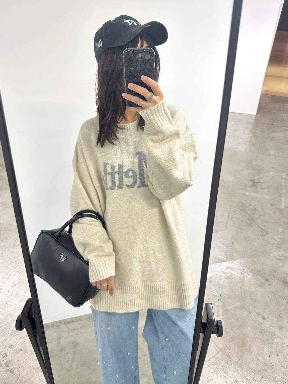 ホワイト系のニット/セーター、ブラック系のショルダーバッグ、ブルー系のデニムパンツを着用したレディースの冬コーディネートの2枚目の写真