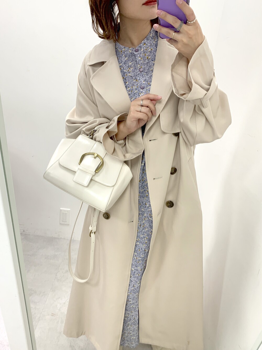 ベージュ系のトレンチコート、パープル系のワンピース、ホワイト系のブーツを着用したレディースの冬コーディネートの2枚目の写真