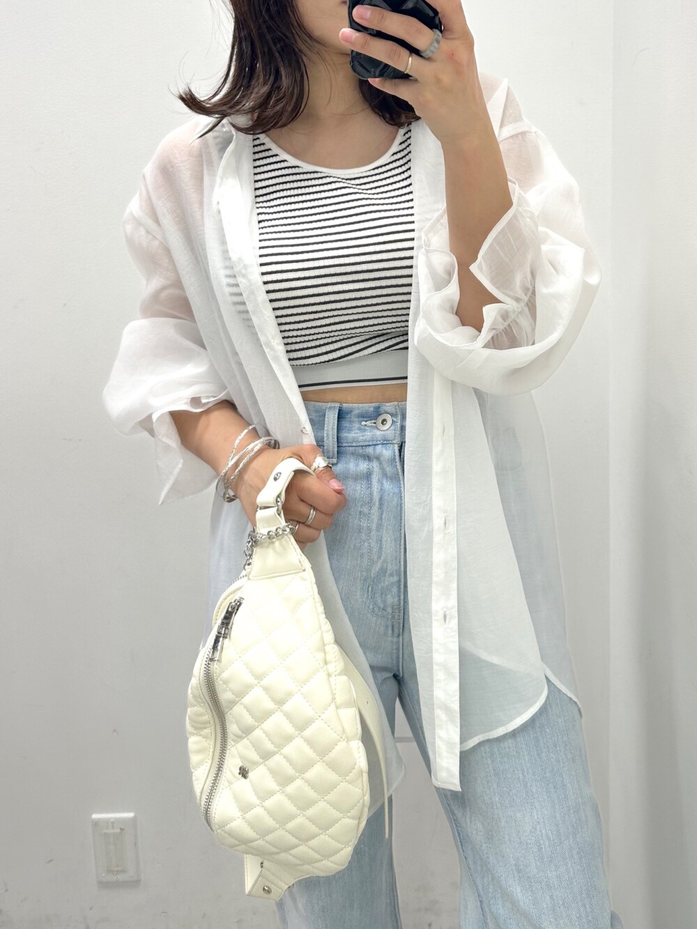 ブルー系のデニムパンツ、ブラック系のタンクトップ、ホワイト系のシャツ/ブラウスを着用したレディースの春コーディネートの2枚目の写真