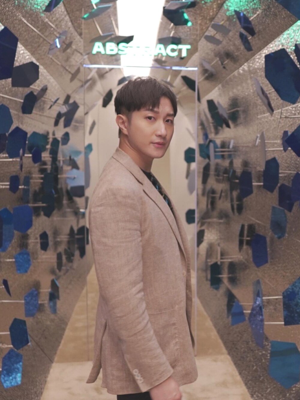 ベージュ系のテーラードジャケット、ブラウン系のドレスシューズ、ブラック系のサングラスを着用したメンズの秋コーディネートの2枚目の写真