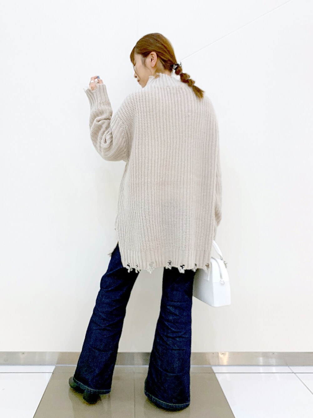 ベージュ系のニット/セーター、ブルー系のデニムパンツ、ブラック系のブーツを着用したレディースの秋コーディネートの2枚目の写真