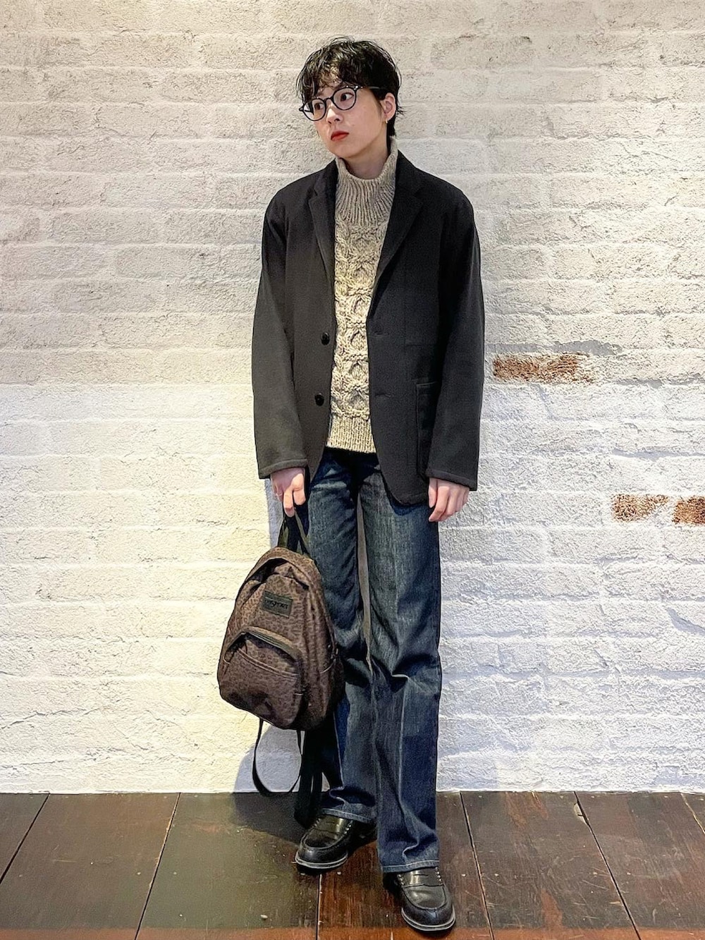 グレー系のニット/セーター、ブラック系のテーラードジャケット、ブルー系のデニムパンツを着用したレディースの冬コーディネートの2枚目の写真