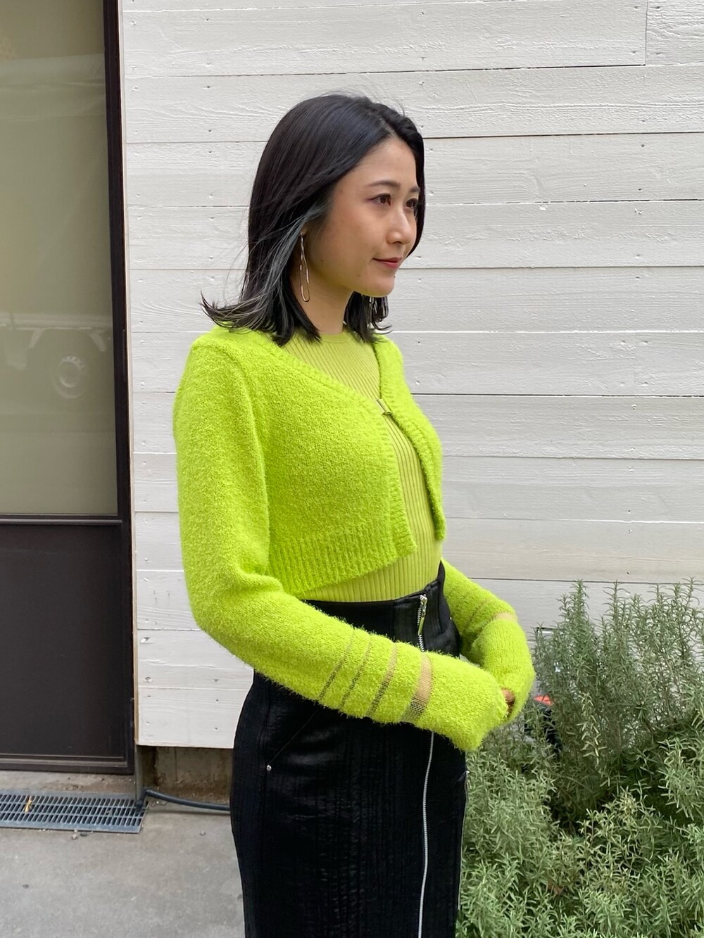 グリーン系のニット/セーター、ブラック系のスカートを着用したレディースの冬コーディネートの4枚目の写真