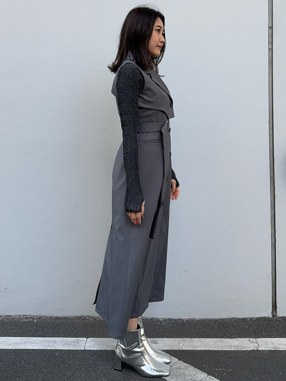 ブラック系のニット/セーター、グレー系のジャンパースカートを着用したレディースの冬コーディネートの2枚目の写真