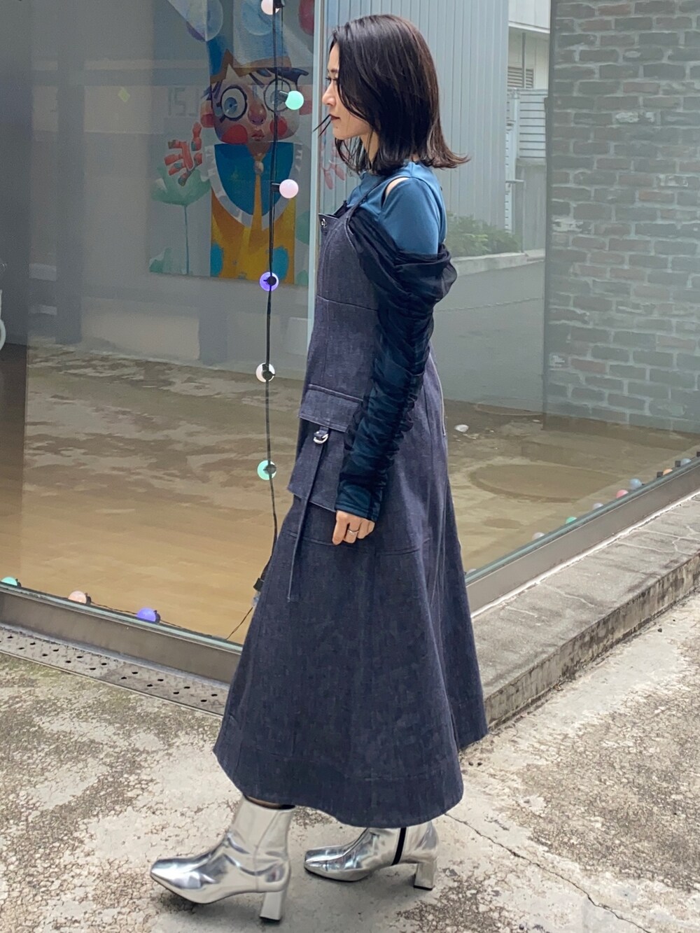 ブルー系のジャンパースカート、グリーン系のTシャツ/カットソー、シルバー系のショルダーバッグを着用したレディースの冬コーディネートの4枚目の写真