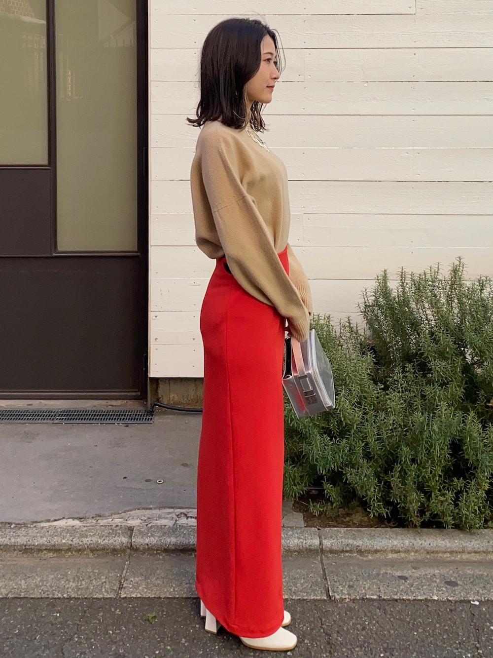 ベージュ系のニット/セーター、レッド系のスカート、シルバー系のショルダーバッグを着用したレディースの冬コーディネートの2枚目の写真