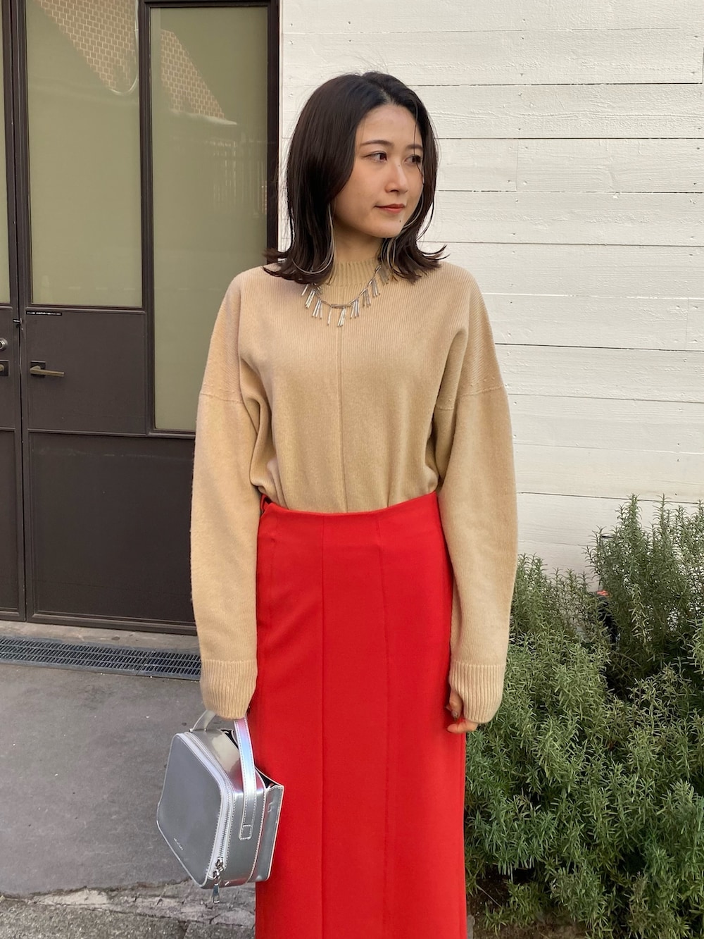 ベージュ系のニット/セーター、レッド系のスカート、シルバー系のショルダーバッグを着用したレディースの冬コーディネートの3枚目の写真