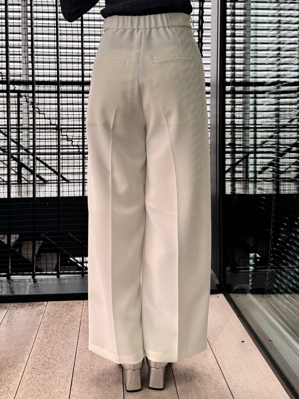 ブラック系のニット/セーター、ホワイト系のスラックスを着用したレディースの冬コーディネートの10枚目の写真