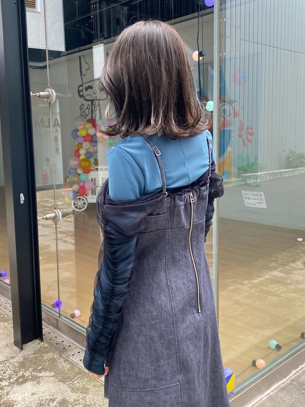 ブルー系のジャンパースカート、グリーン系のTシャツ/カットソー、シルバー系のショルダーバッグを着用したレディースの冬コーディネートの6枚目の写真