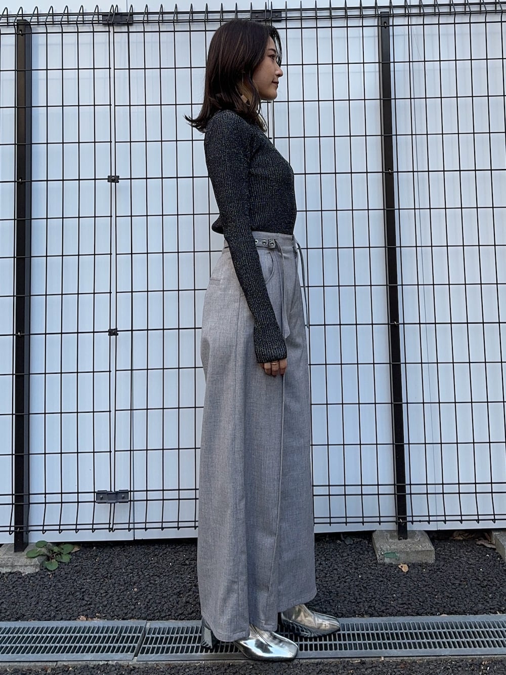 ブラック系のニット/セーター、グレー系のスラックスを着用したレディースの冬コーディネートの2枚目の写真