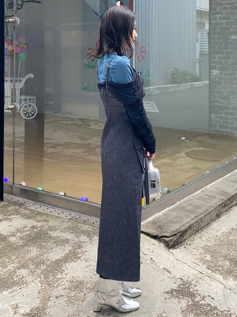 ブルー系のジャンパースカート、グリーン系のTシャツ/カットソー、シルバー系のショルダーバッグを着用したレディースの冬コーディネートの2枚目の写真