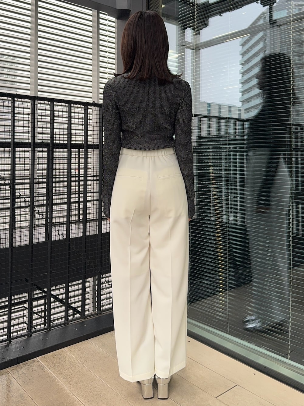 ブラック系のニット/セーター、ホワイト系のスラックスを着用したレディースの冬コーディネートの3枚目の写真