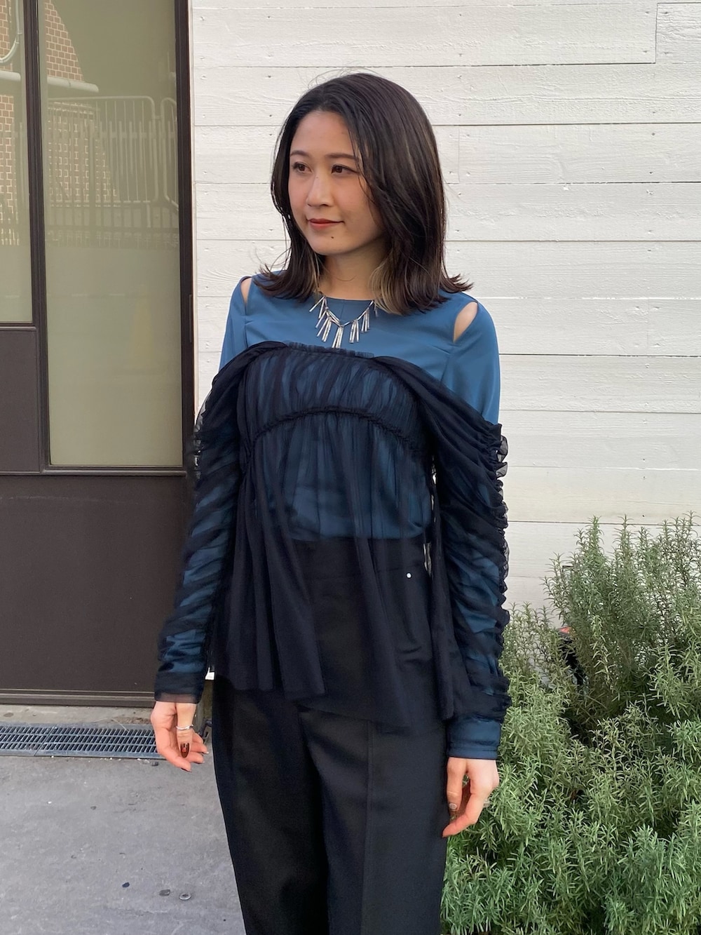 グリーン系のTシャツ/カットソー、ブラック系のスラックスを着用したレディースの冬コーディネートの5枚目の写真