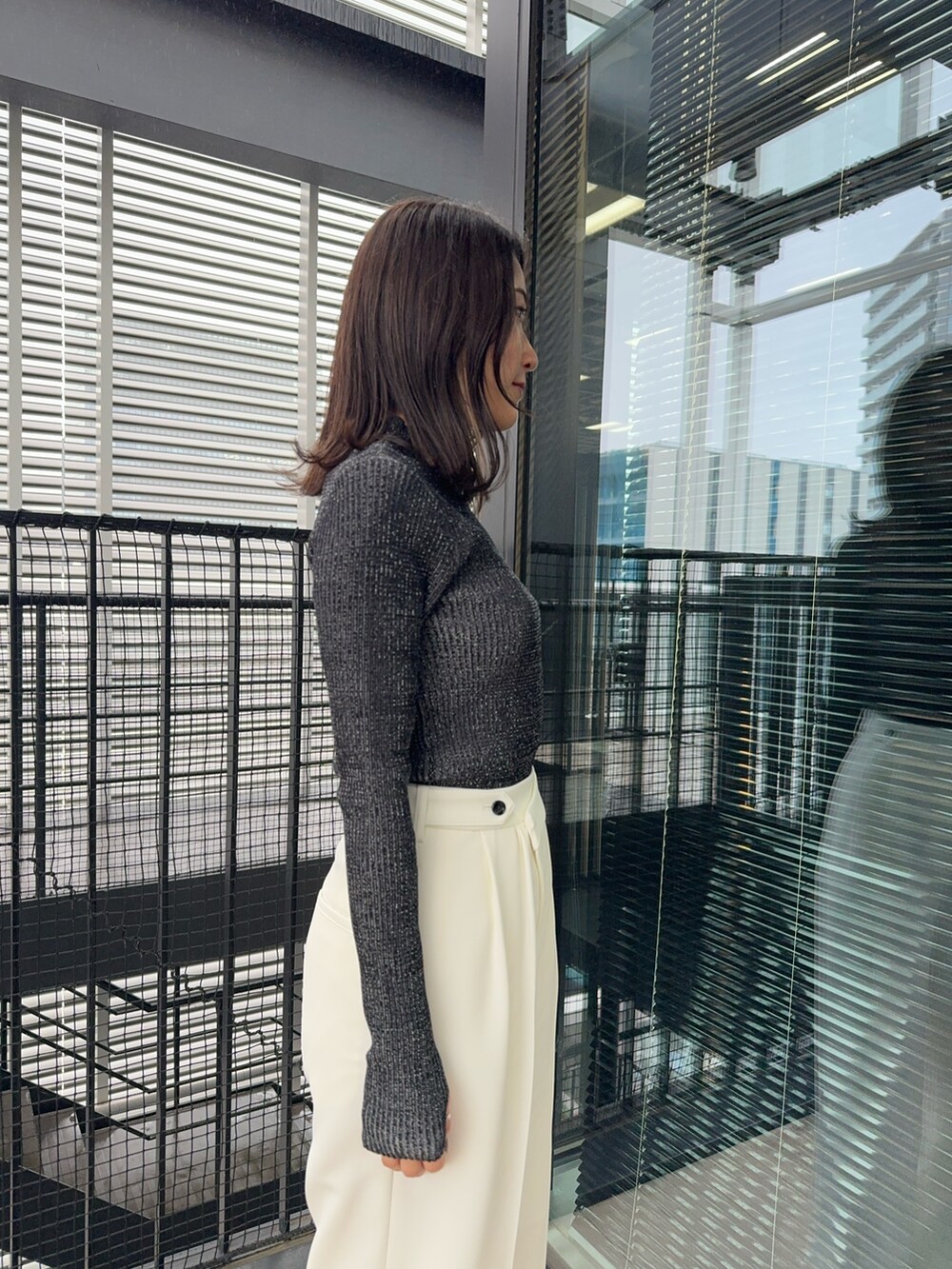 ブラック系のニット/セーター、ホワイト系のスラックスを着用したレディースの冬コーディネートの4枚目の写真