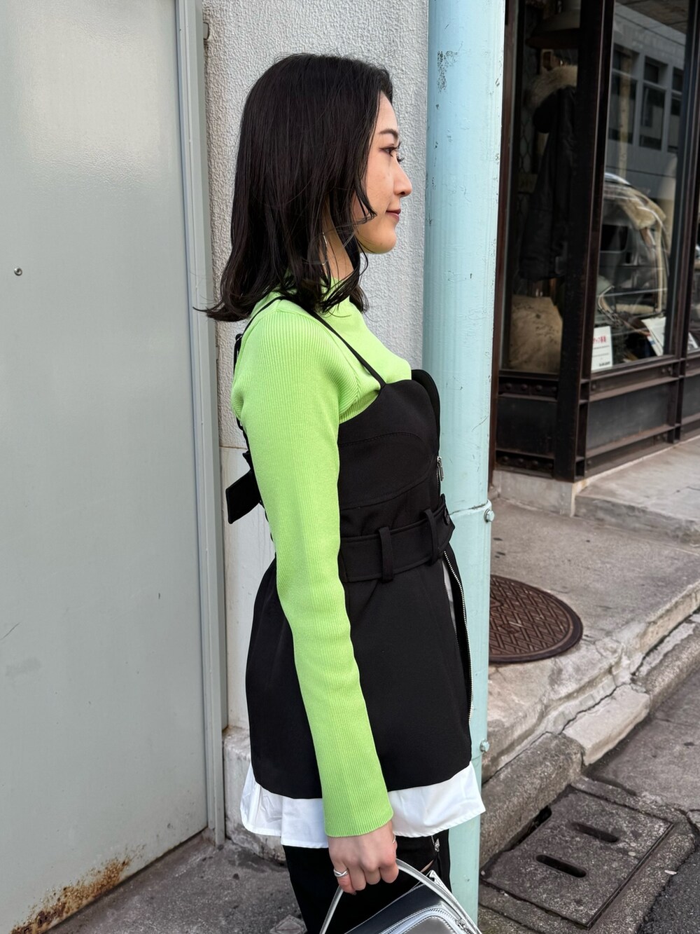 グリーン系のニット/セーター、ブラック系のベスト、ブラック系のその他パンツを着用したレディースの冬コーディネートの5枚目の写真