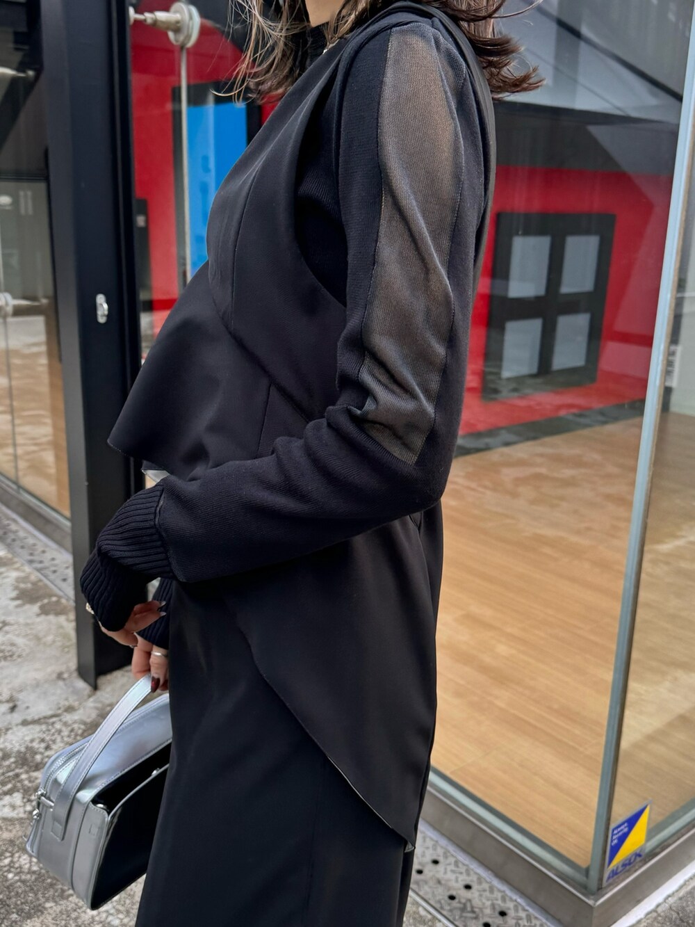 ブラック系のジャンパースカート、ブラック系のニット/セーター、シルバー系のショルダーバッグを着用したレディースの冬コーディネートの6枚目の写真