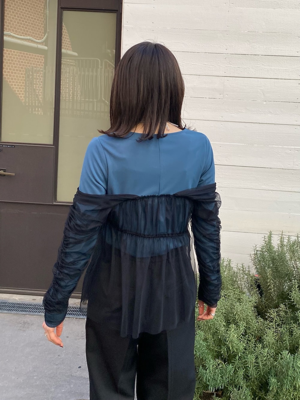 グリーン系のTシャツ/カットソー、ブラック系のスラックスを着用したレディースの冬コーディネートの7枚目の写真