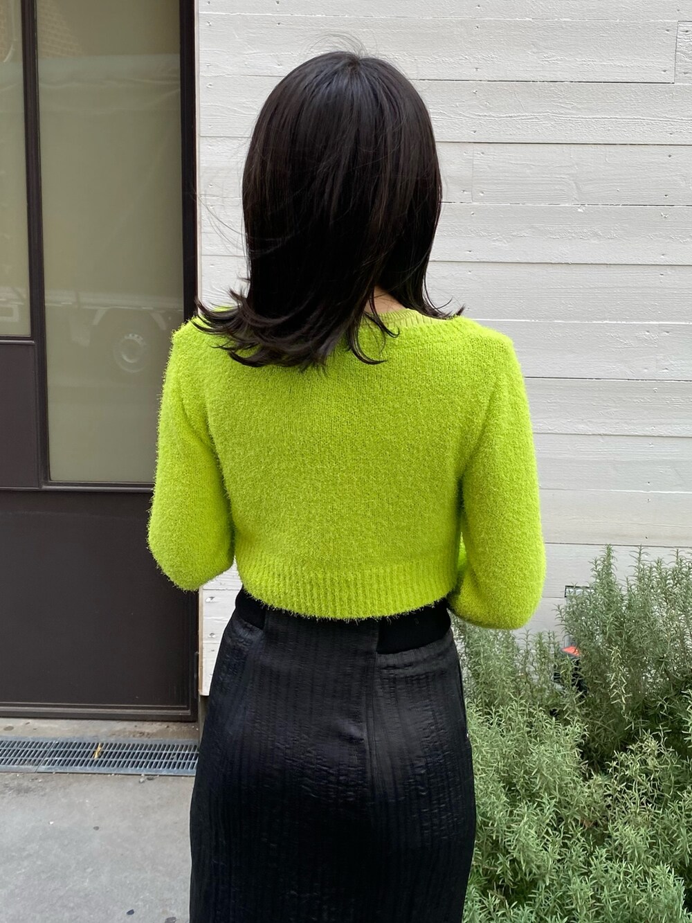 グリーン系のニット/セーター、ブラック系のスカートを着用したレディースの冬コーディネートの5枚目の写真