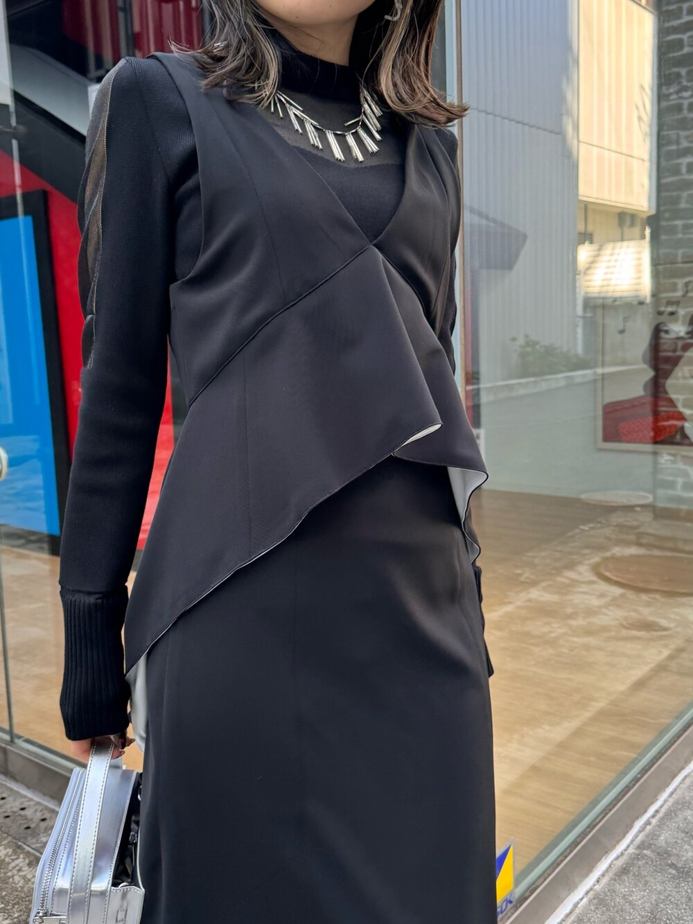 ブラック系のジャンパースカート、ブラック系のニット/セーター、シルバー系のショルダーバッグを着用したレディースの冬コーディネートの4枚目の写真