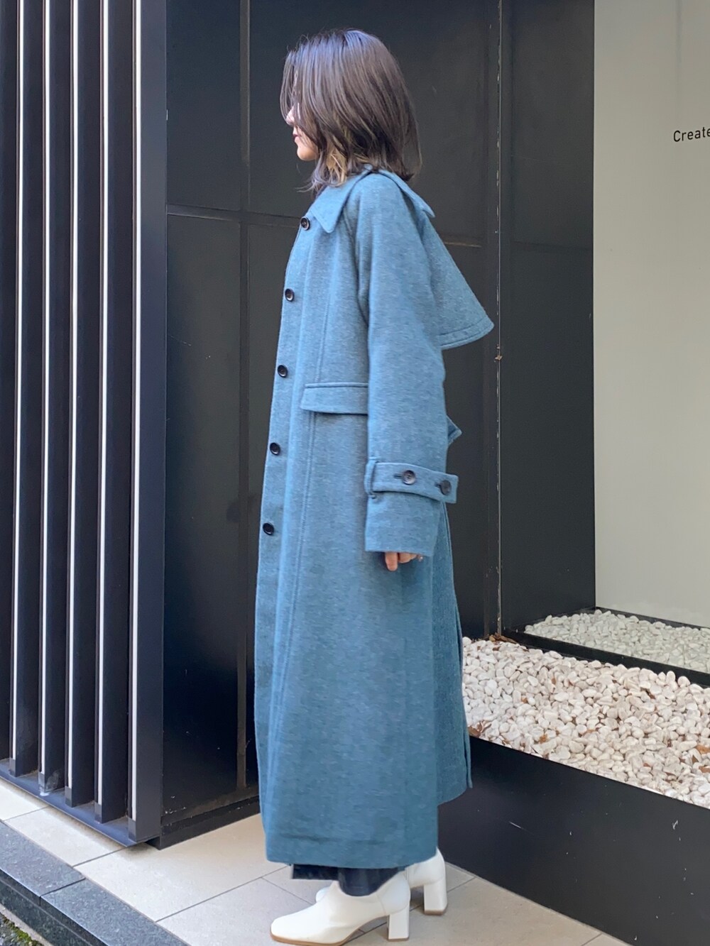 ブルー系のスカート、ブラック系のシャツ/ブラウス、その他のステンカラーコートを着用したレディースの冬コーディネートの2枚目の写真