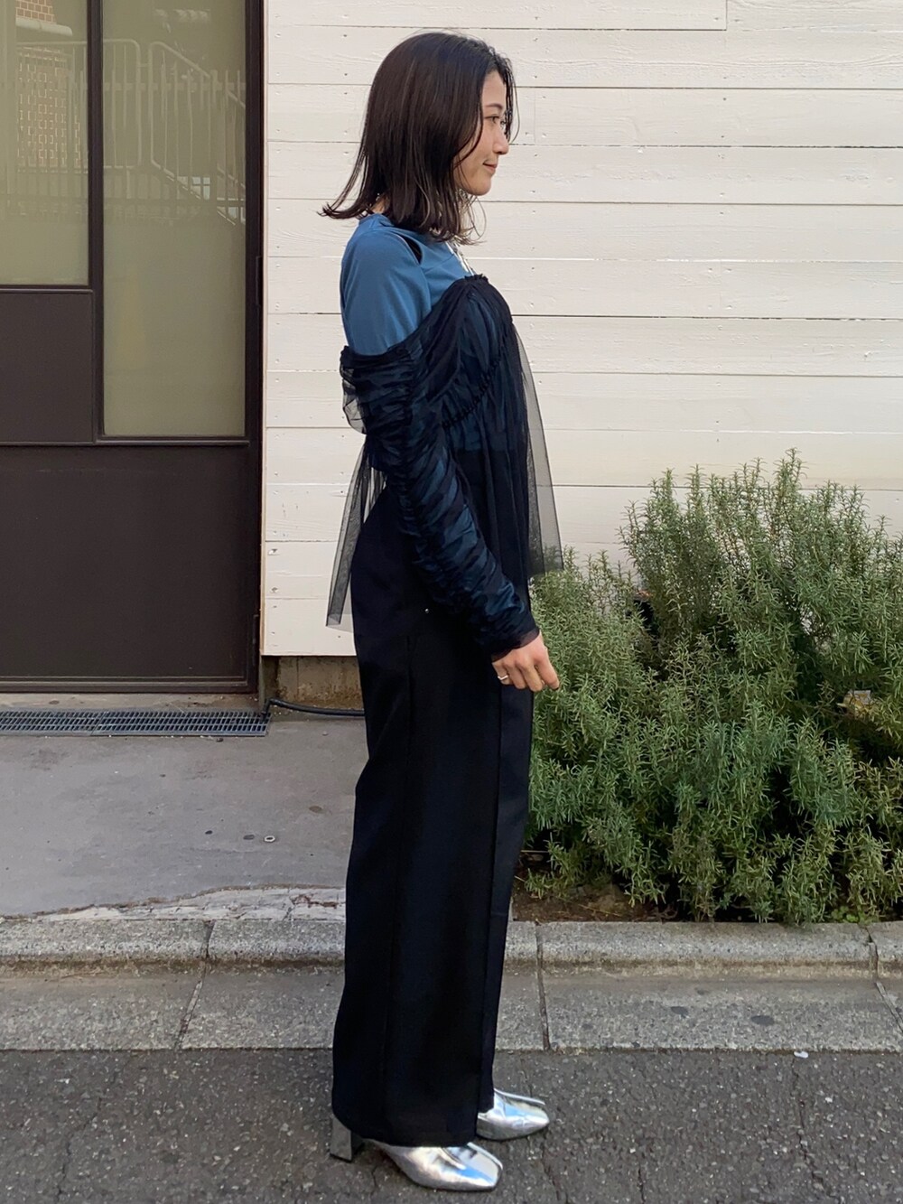 グリーン系のTシャツ/カットソー、ブラック系のスラックスを着用したレディースの冬コーディネートの2枚目の写真