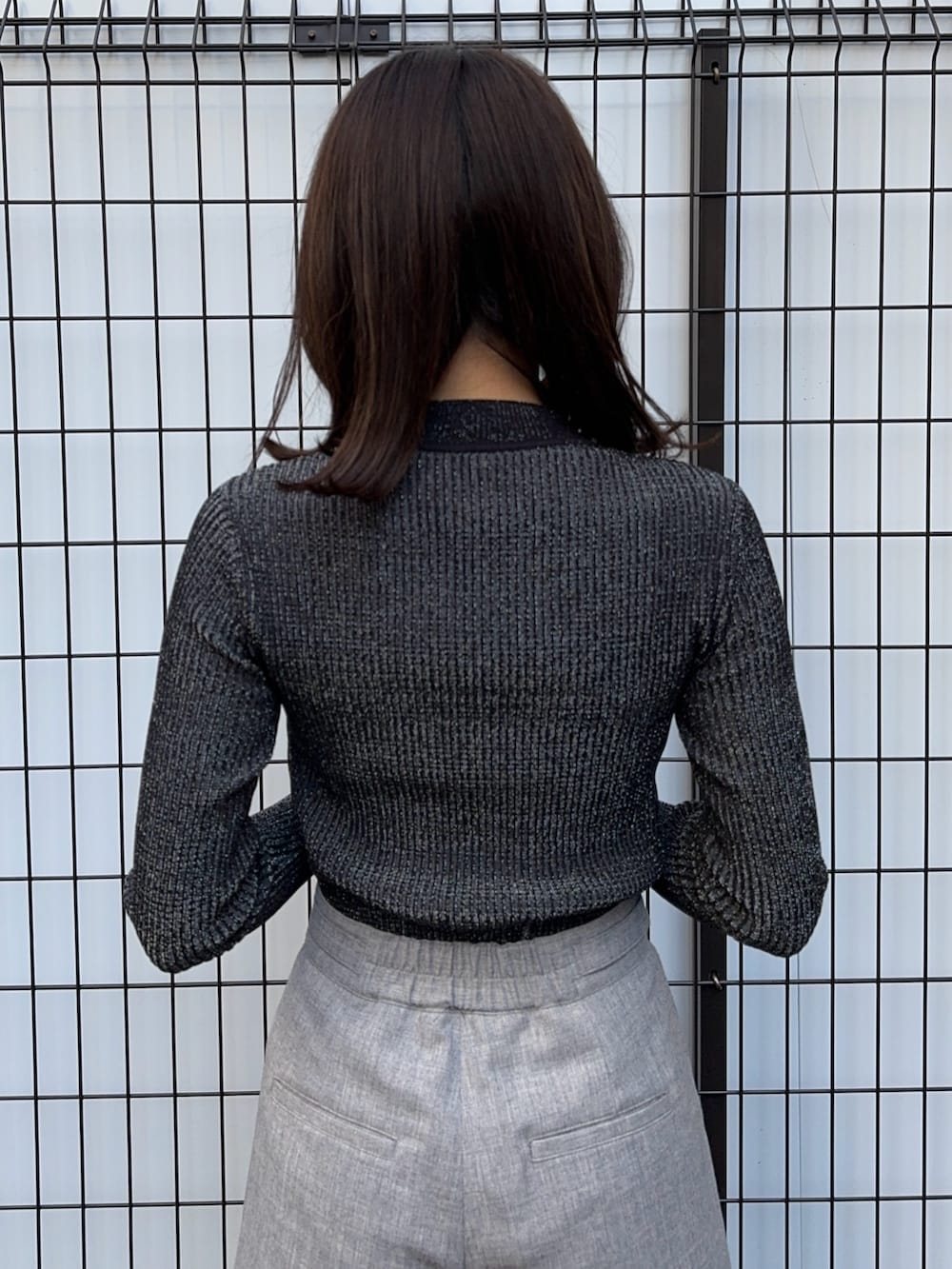 ブラック系のニット/セーター、グレー系のスラックスを着用したレディースの冬コーディネートの5枚目の写真