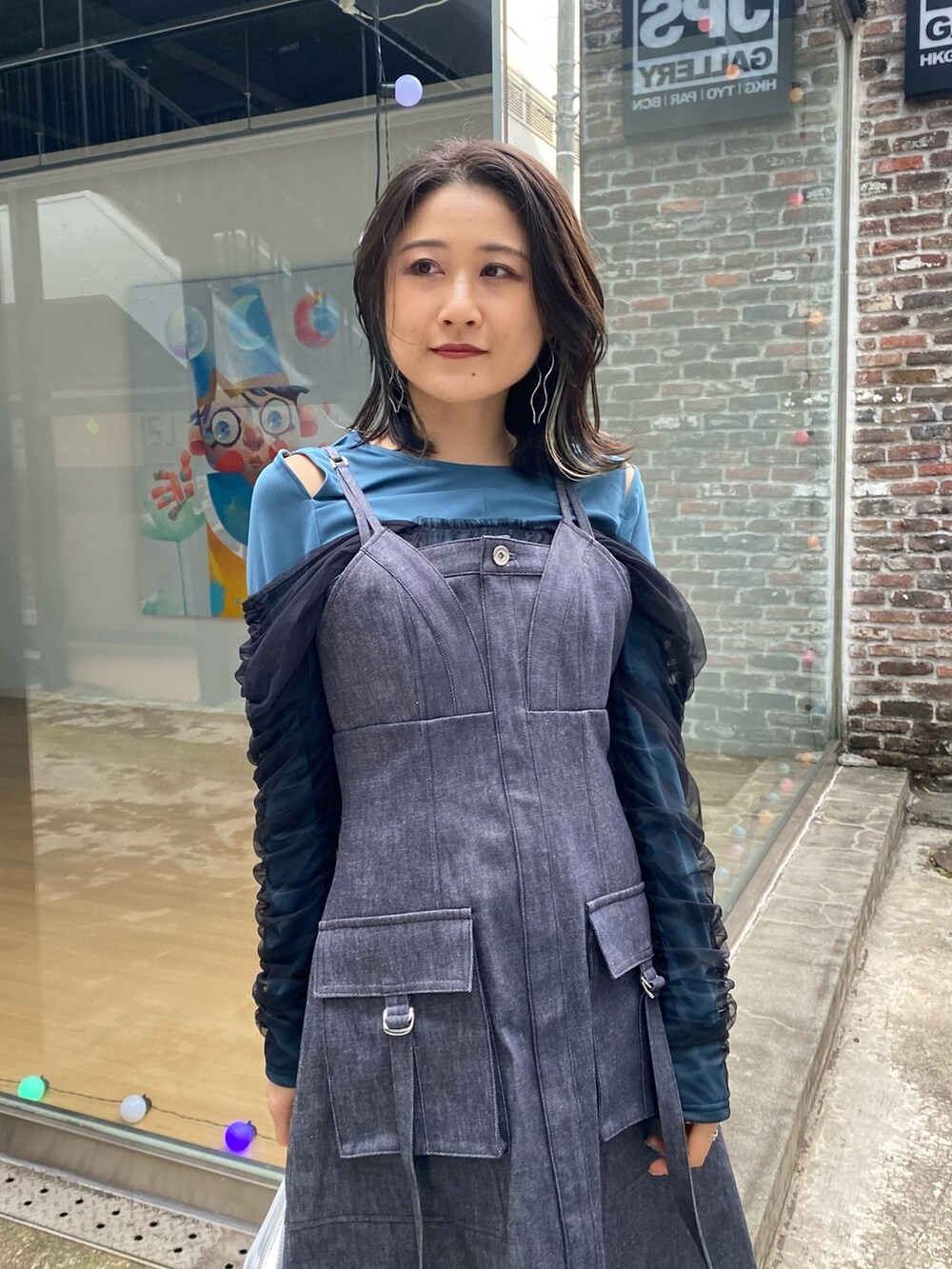 ブルー系のジャンパースカート、グリーン系のTシャツ/カットソー、シルバー系のショルダーバッグを着用したレディースの冬コーディネートの5枚目の写真