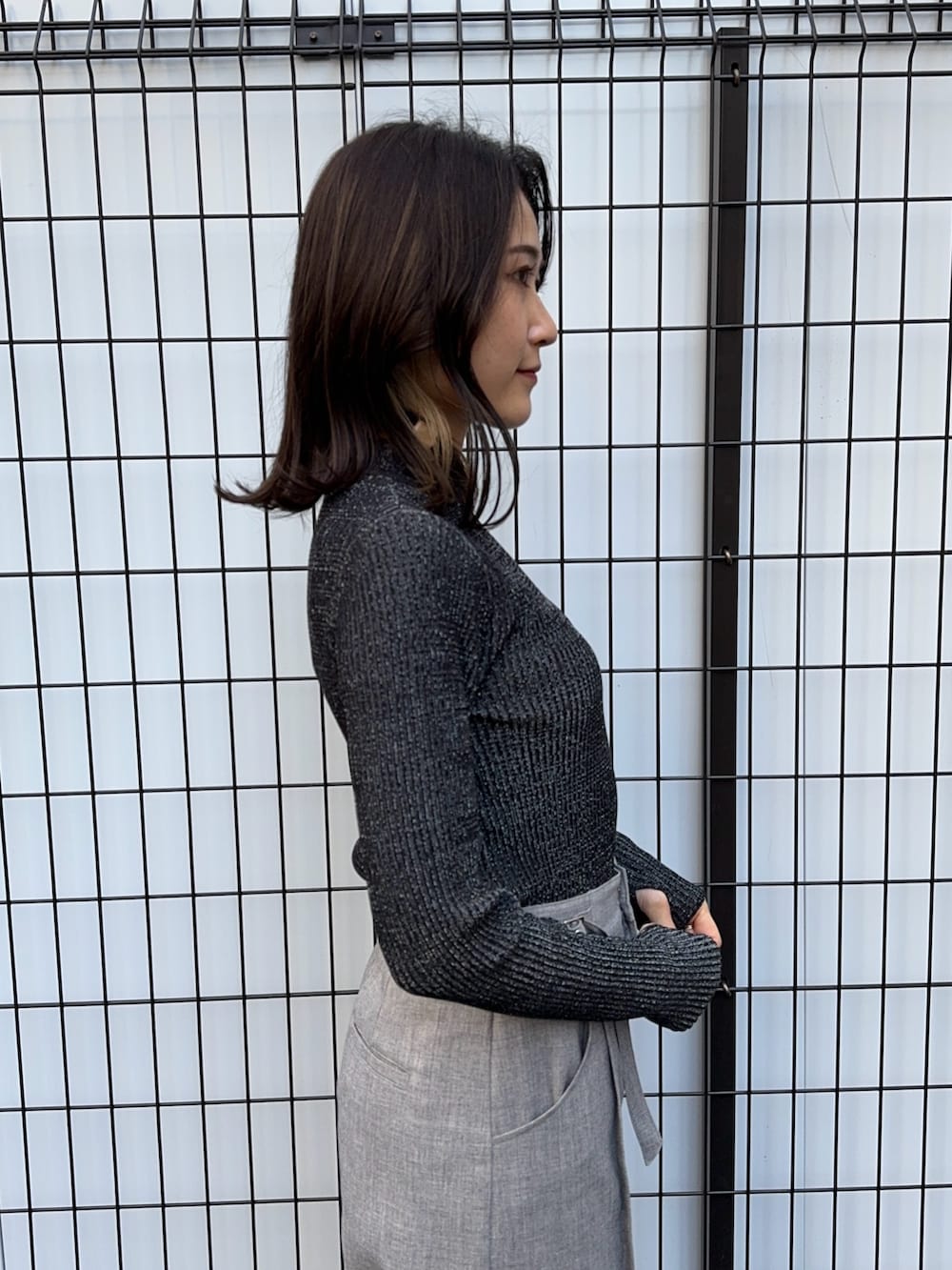 ブラック系のニット/セーター、グレー系のスラックスを着用したレディースの冬コーディネートの4枚目の写真