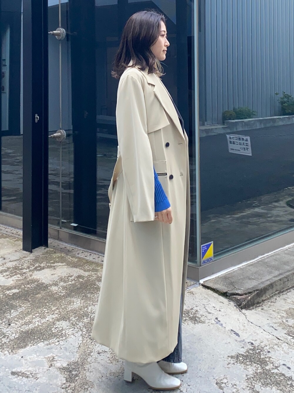 ベージュ系のトレンチコートを着用したレディースの冬コーディネートの2枚目の写真