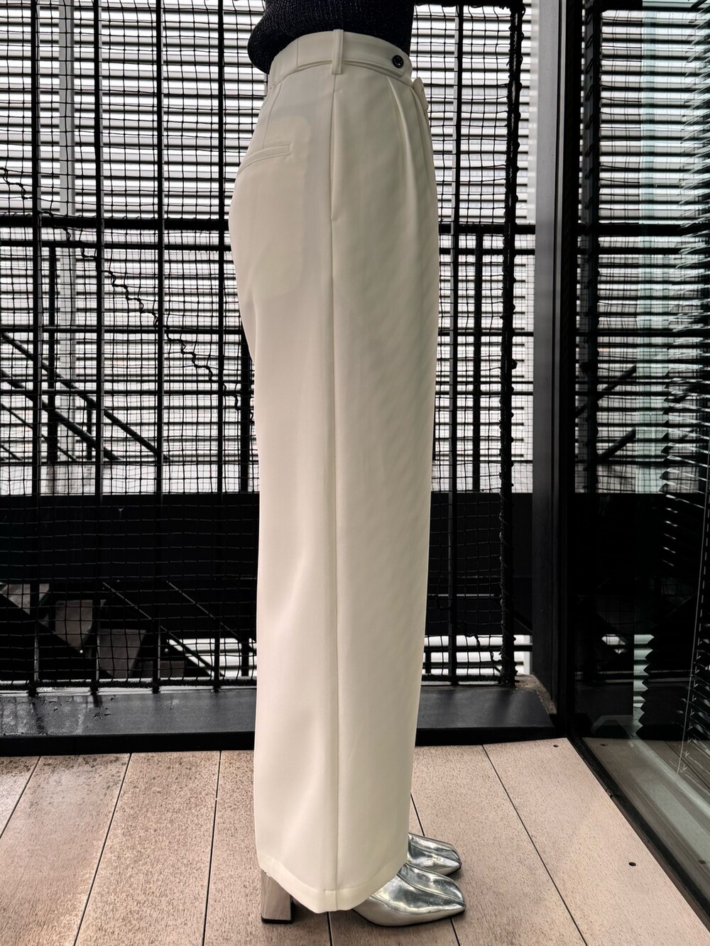 ブラック系のニット/セーター、ホワイト系のスラックスを着用したレディースの冬コーディネートの9枚目の写真