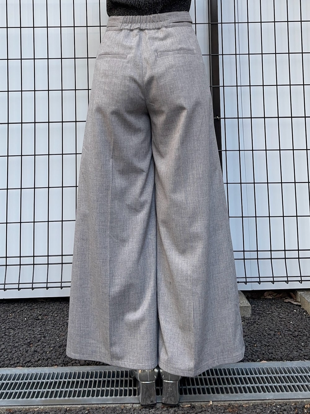 ブラック系のニット/セーター、グレー系のスラックスを着用したレディースの冬コーディネートの8枚目の写真