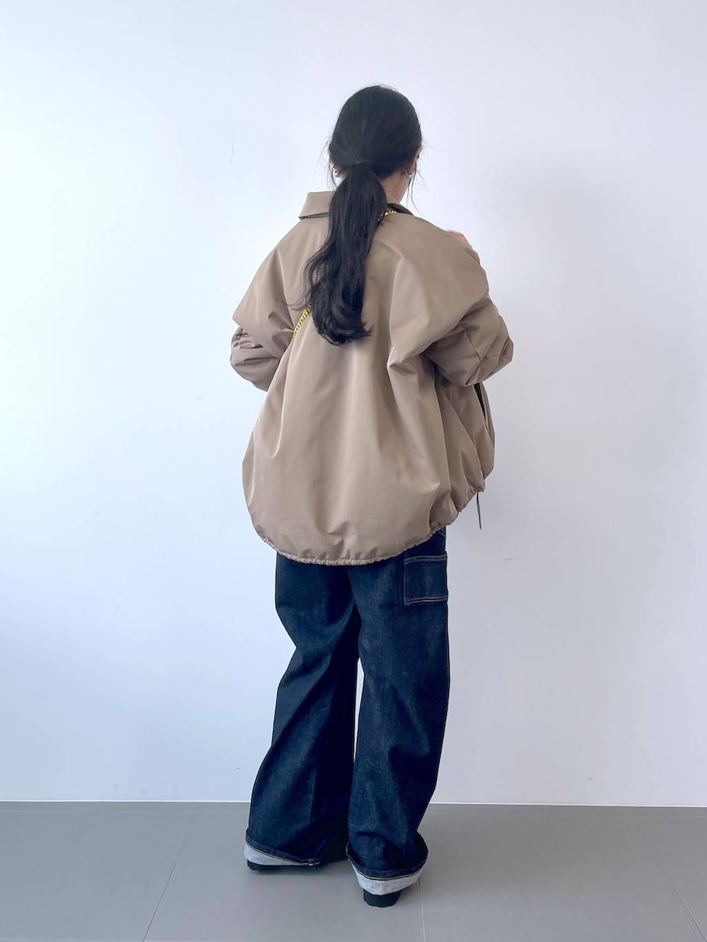 ブルー系のデニムパンツ、ブラック系のショルダーバッグ、ホワイト系のTシャツ/カットソーを着用したレディースの秋コーディネートの3枚目の写真