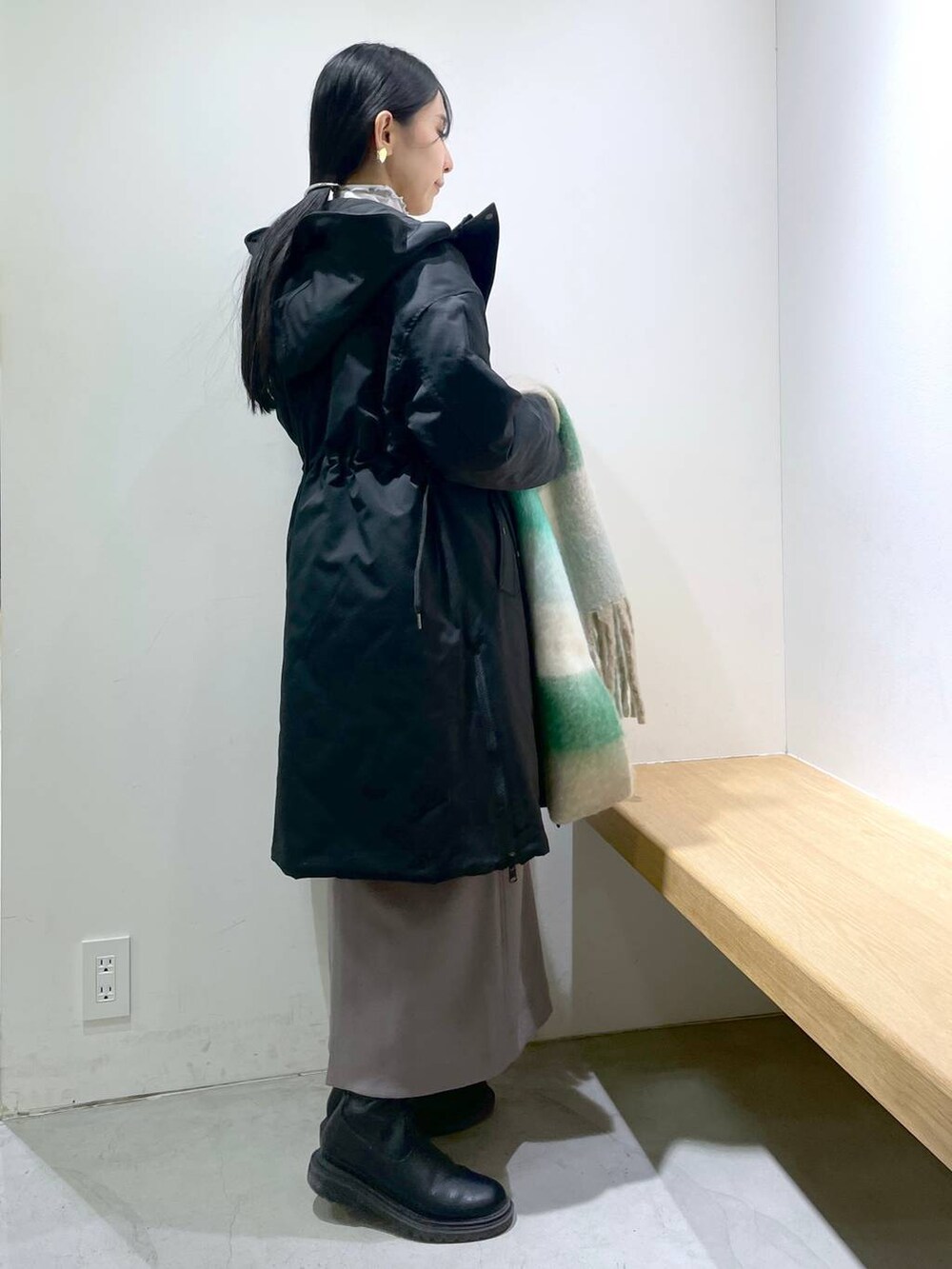 グレー系のワンピース、ブラック系のダウンジャケット/コート、ホワイト系のストール/ショールを着用したレディースの冬コーディネートの2枚目の写真