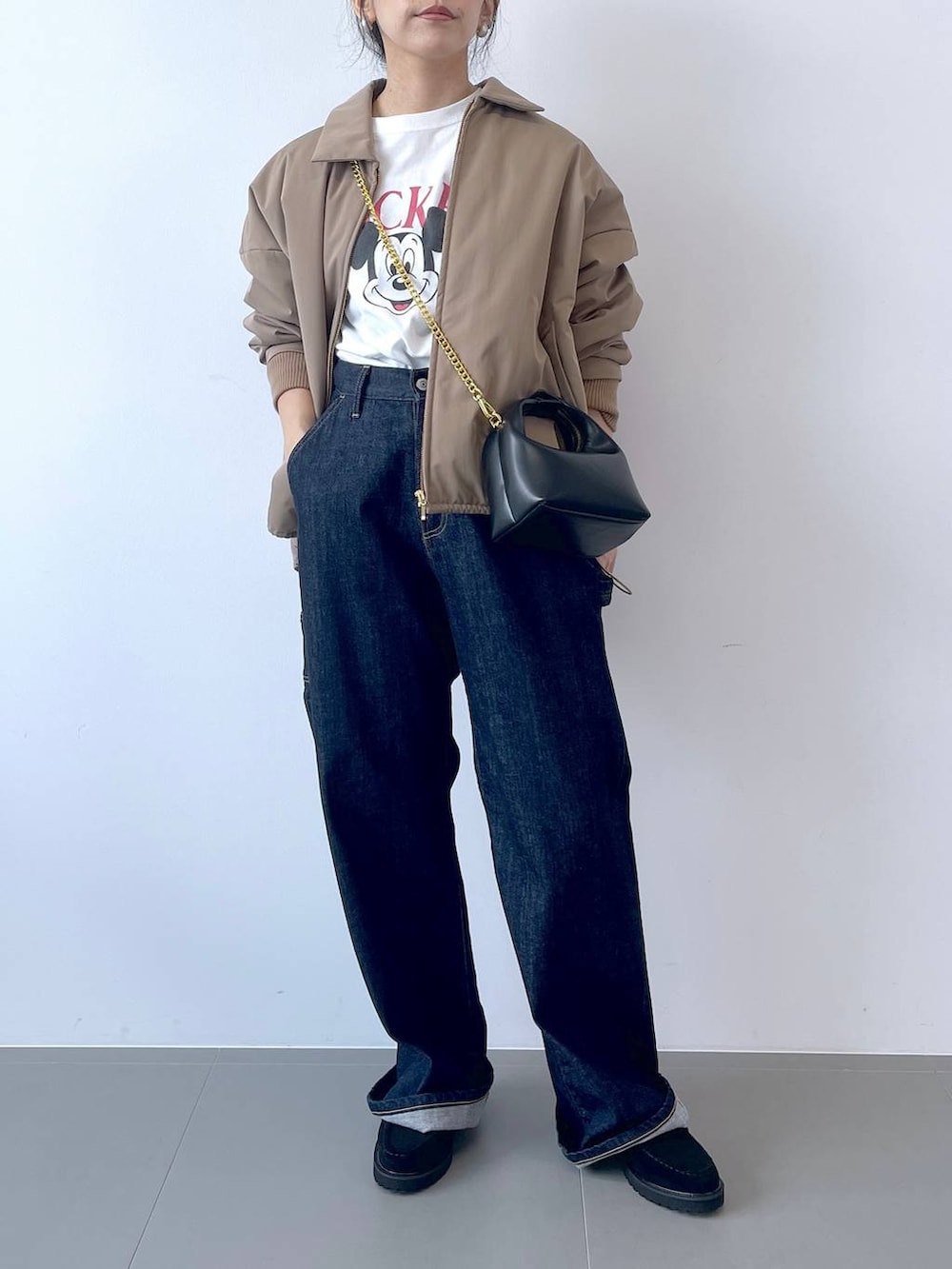 ブルー系のデニムパンツ、ブラック系のショルダーバッグ、ホワイト系のTシャツ/カットソーを着用したレディースの秋コーディネートの4枚目の写真