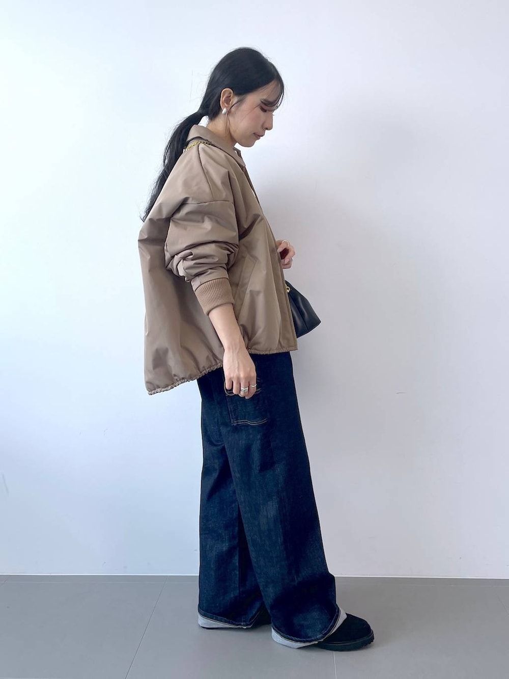 ブルー系のデニムパンツ、ブラック系のショルダーバッグ、ホワイト系のTシャツ/カットソーを着用したレディースの秋コーディネートの2枚目の写真