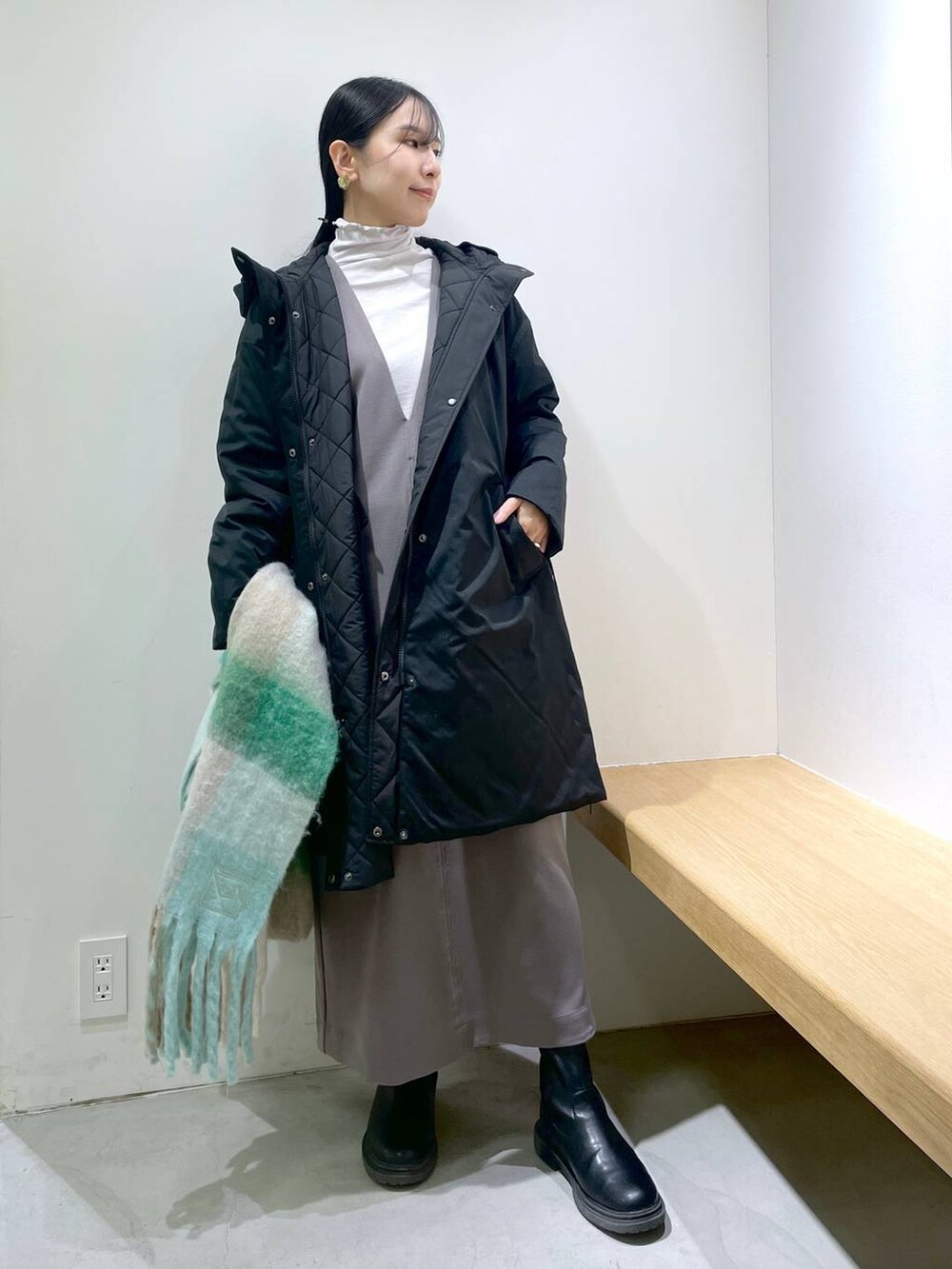 グレー系のワンピース、ブラック系のダウンジャケット/コート、ホワイト系のストール/ショールを着用したレディースの冬コーディネートの4枚目の写真