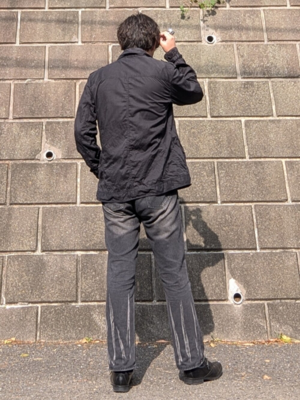 ブラック系のデニムパンツ、ブラック系のシューズ、ホワイト系のTシャツ/カットソーを着用したメンズの夏コーディネートの3枚目の写真